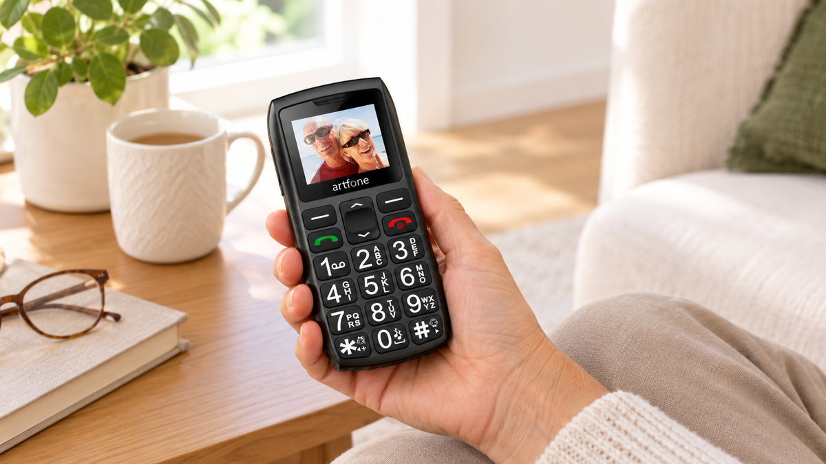 Main tenant un téléphone portable à grosses touches dans son salon